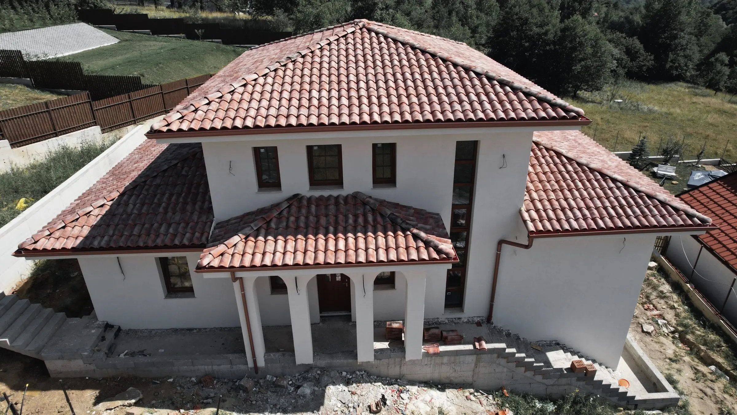 Vilă cu portic cu coloane și acoperiș din țiglă ceramică, văzută din dronă