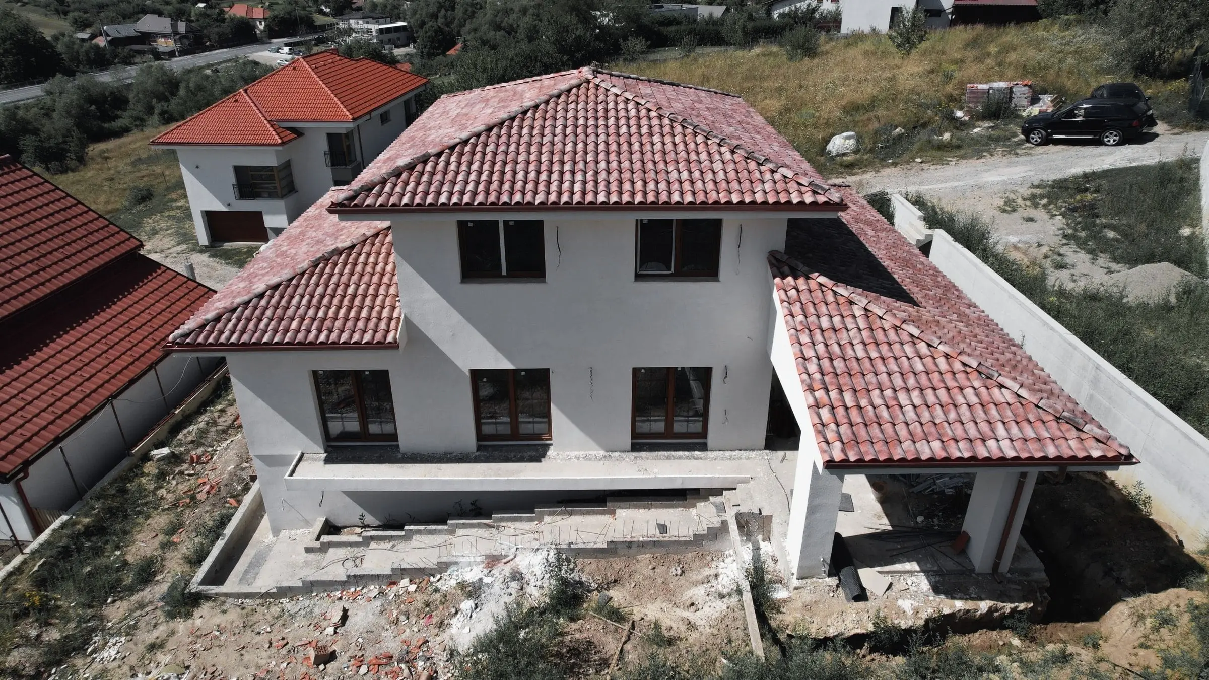 Vilă cu acoperiș din țiglă ceramică roșie, văzută din dronă, cu scările neterminate