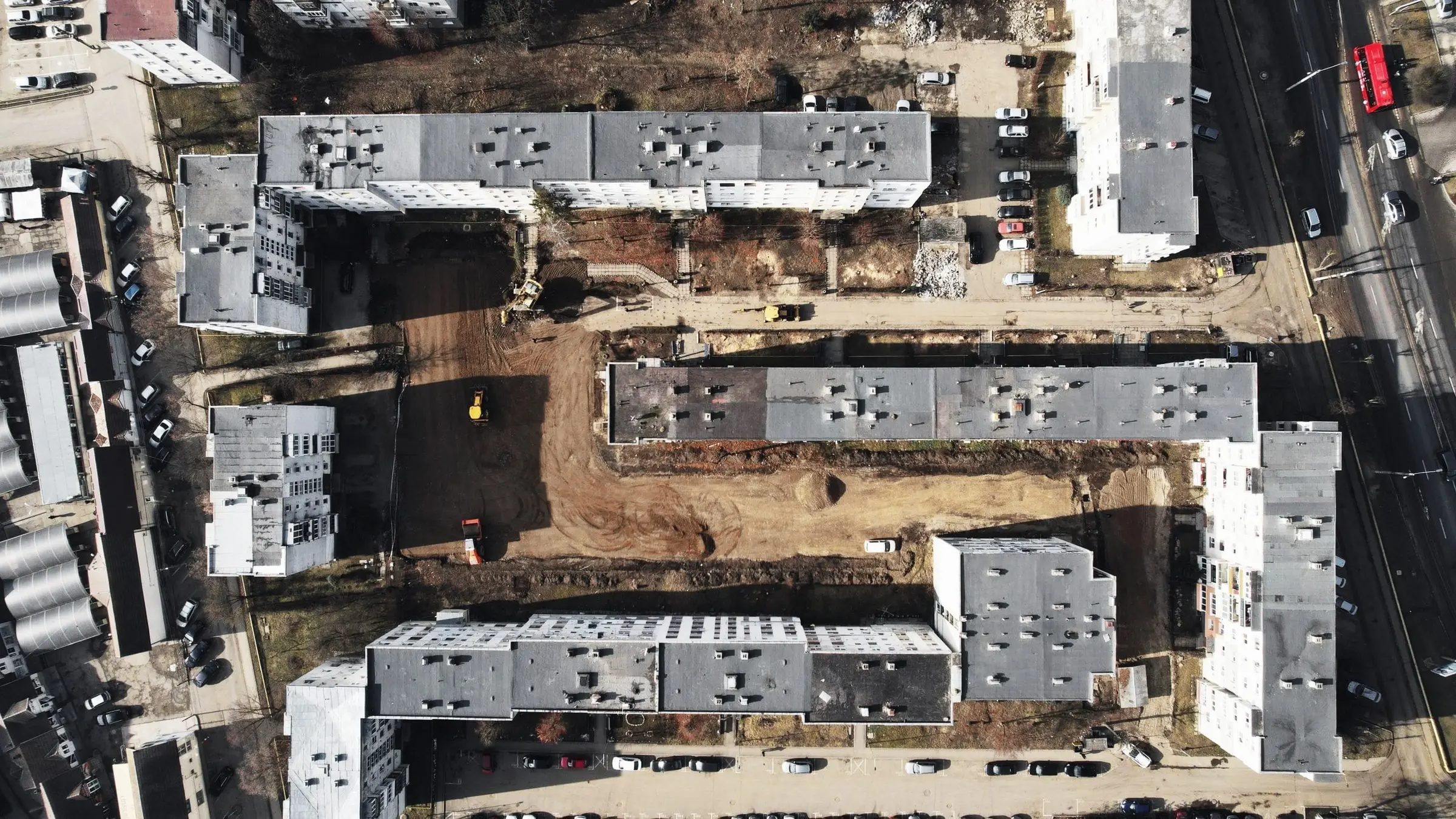 Vedere aeriană de sus a unui ansamblu de blocuri în construcție, lângă o stradă
