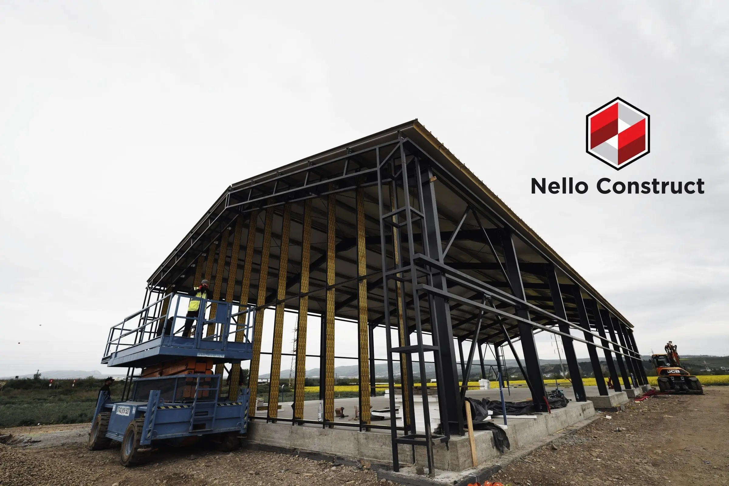 Structură metalică a unei hale în construcție, cu platformă elevatoare albastră
