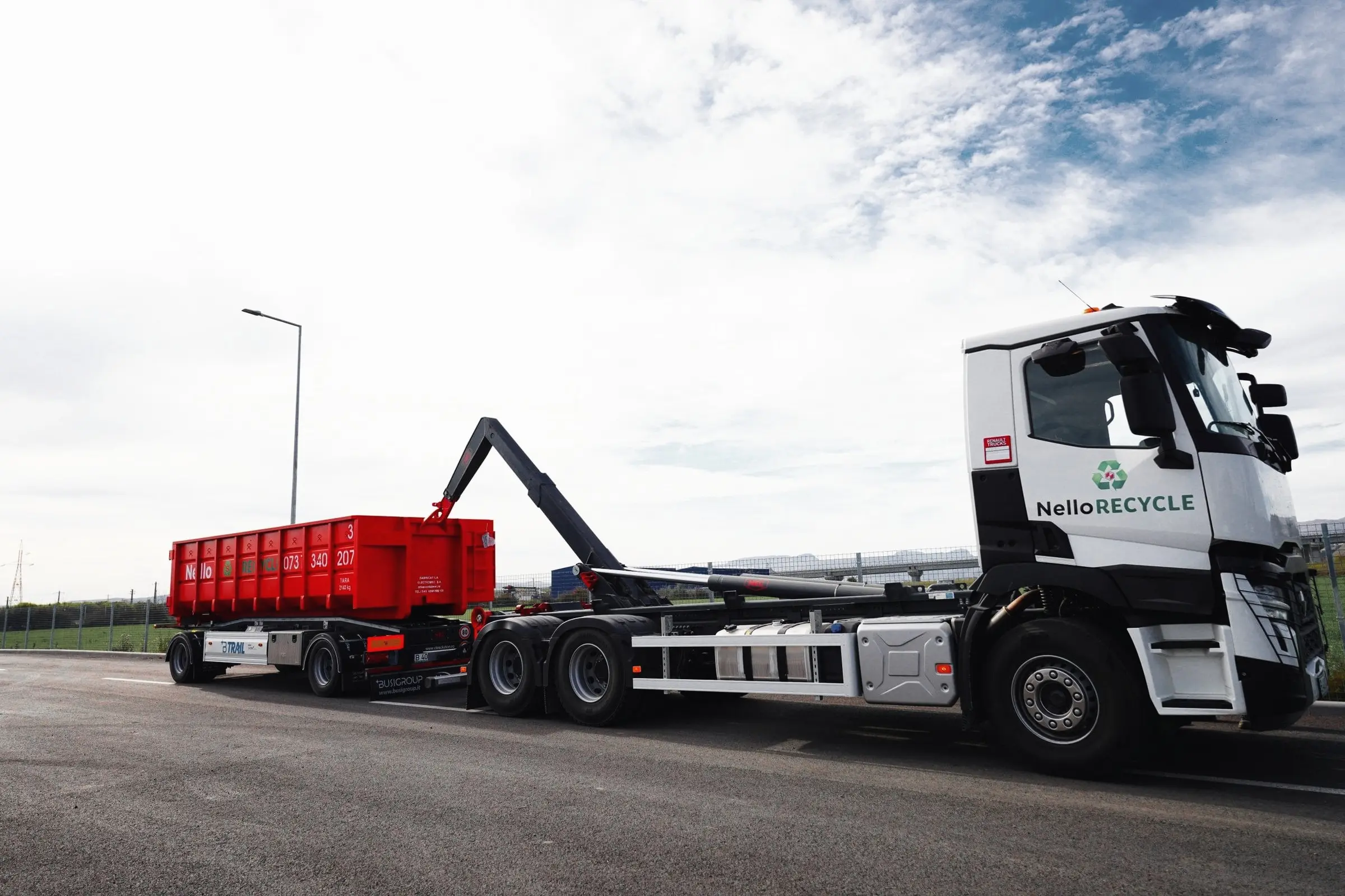 Camion hook-lift Nello Recycle cu remorcă și container roșu, văzut din lateral
