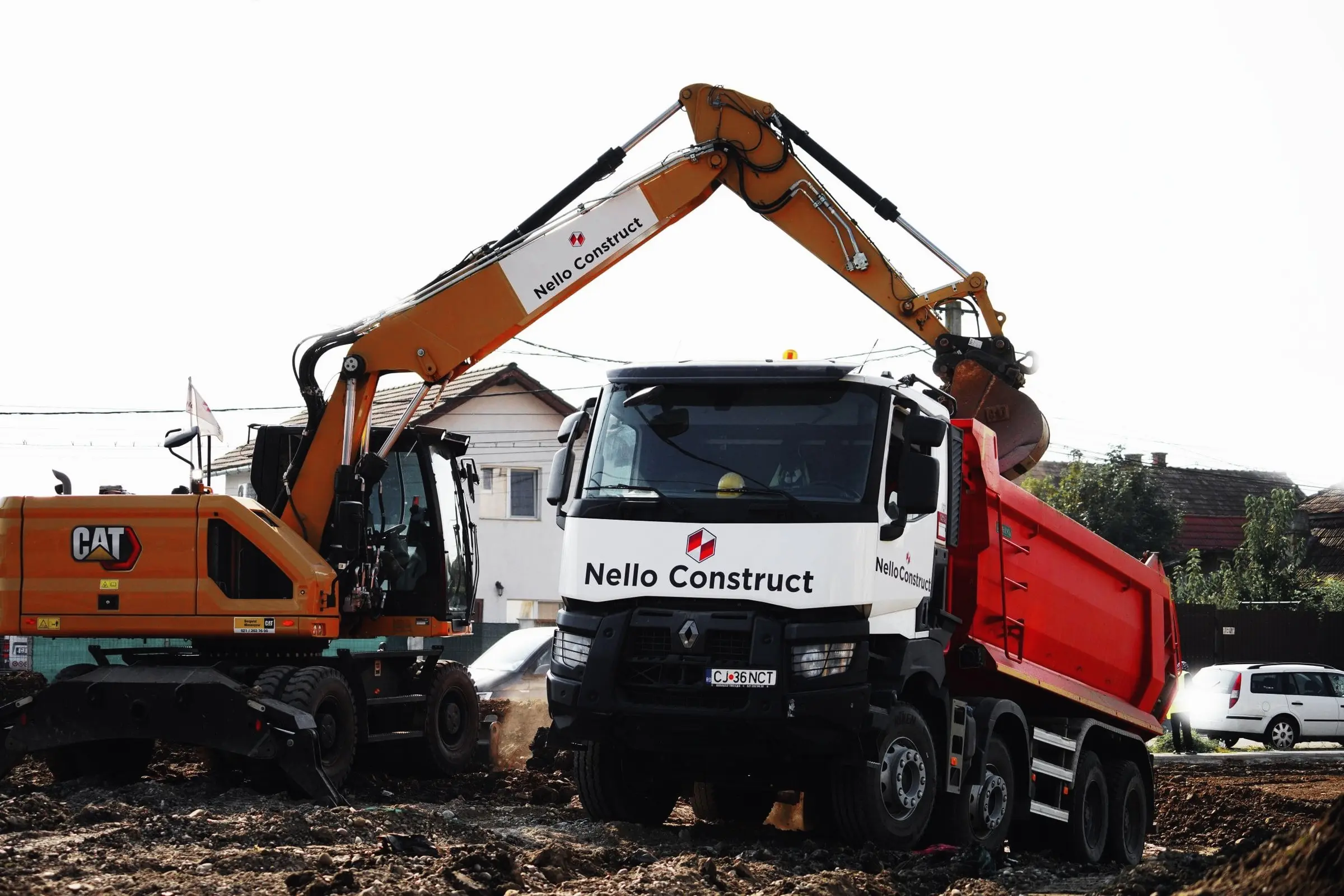 Excavator pe roți și autobasculantă Nello Construct pe un șantier cu pământ
