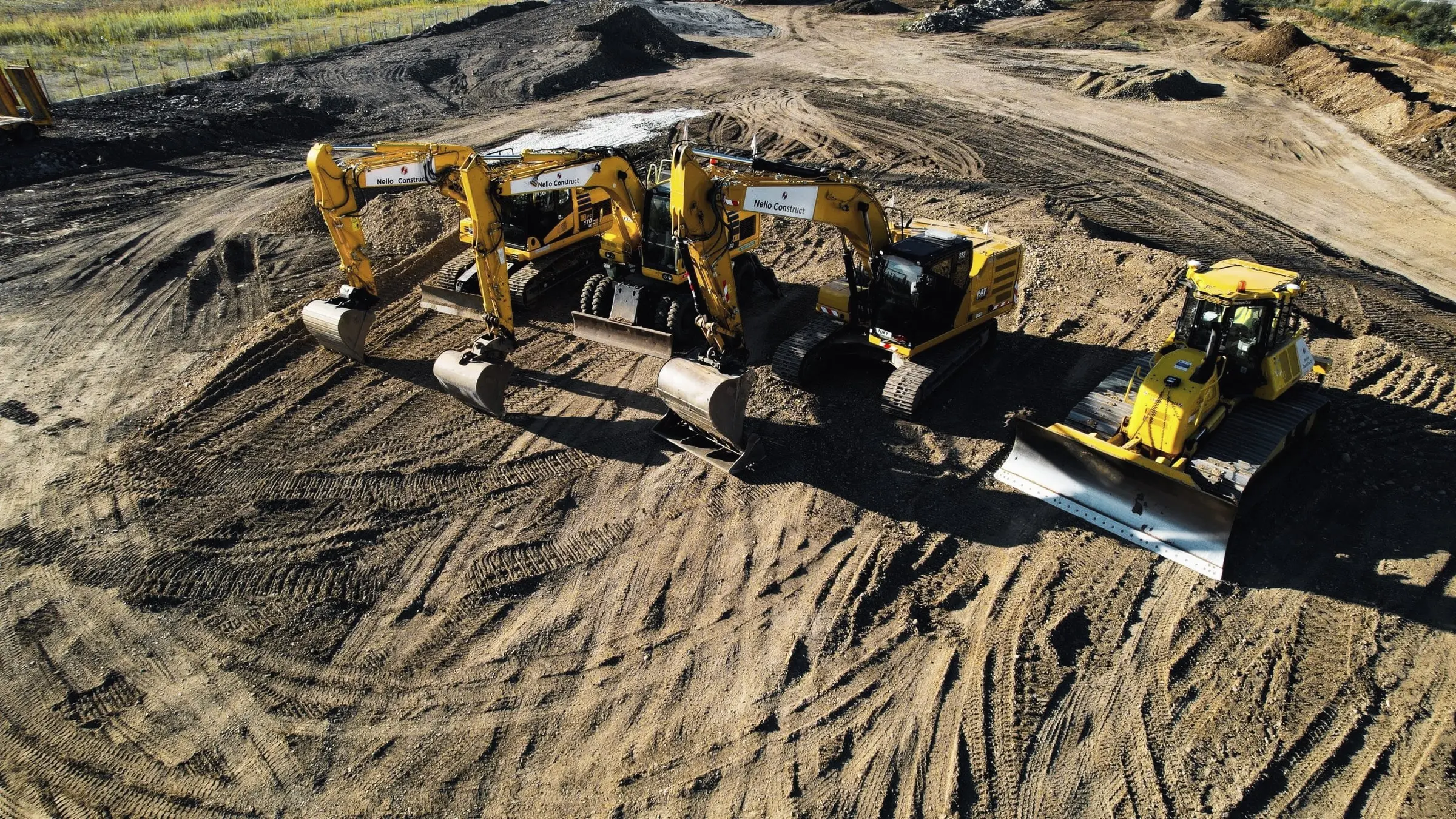 Vedere aeriană cu trei excavatoare și un buldozer galben pe teren de pământ